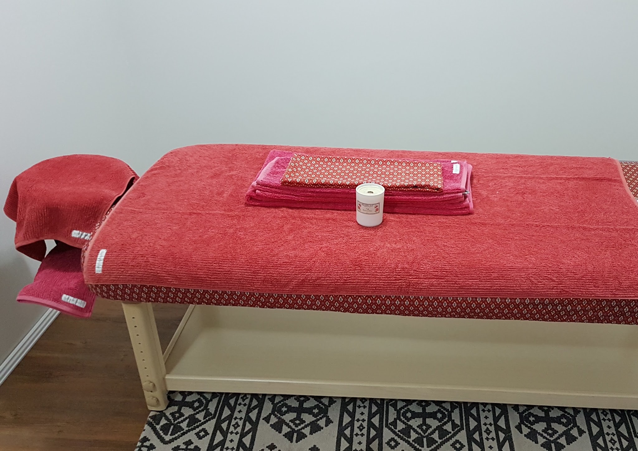 Close view of the massage table with folded towels, patterned cloth and a candle